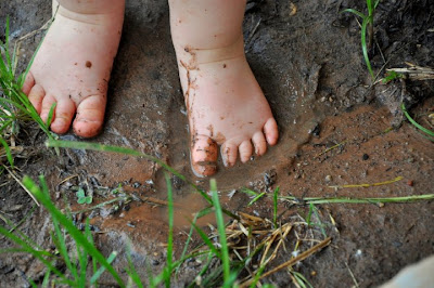 bare baby feet exploring mud